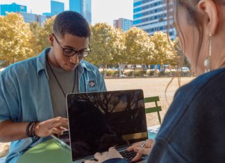 man and woman sitting while using MacBook Pro