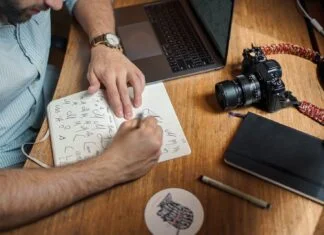 man writing on paper in front of DSLR