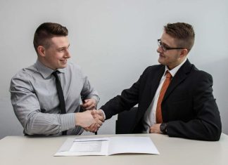 two men facing each other while shake hands and smiling